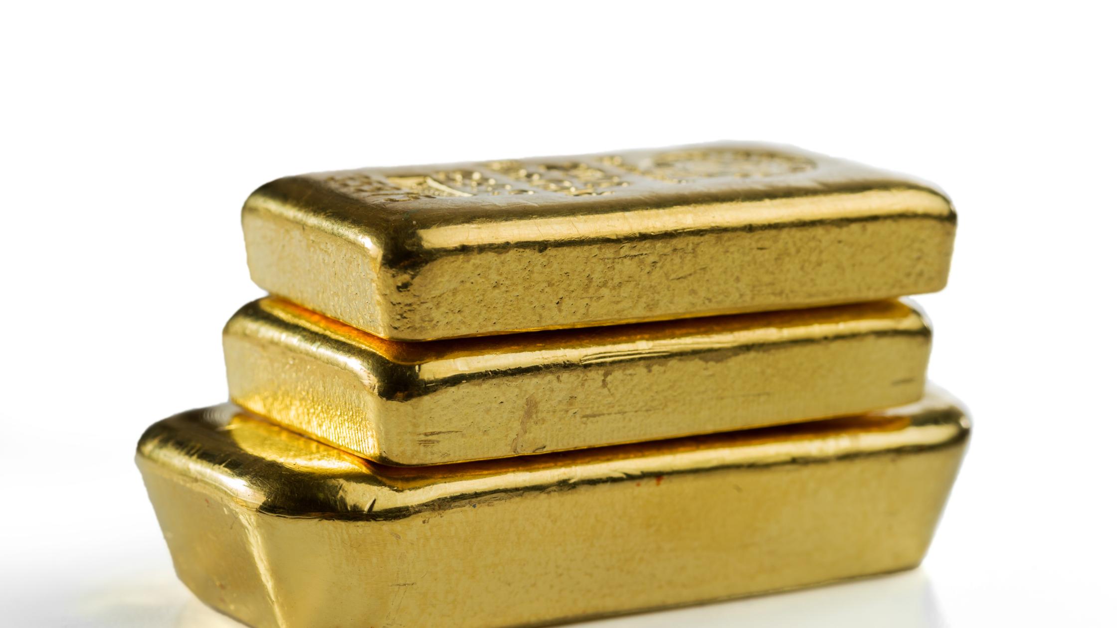Three cast gold bars are in a pile. Isolated on a white background.